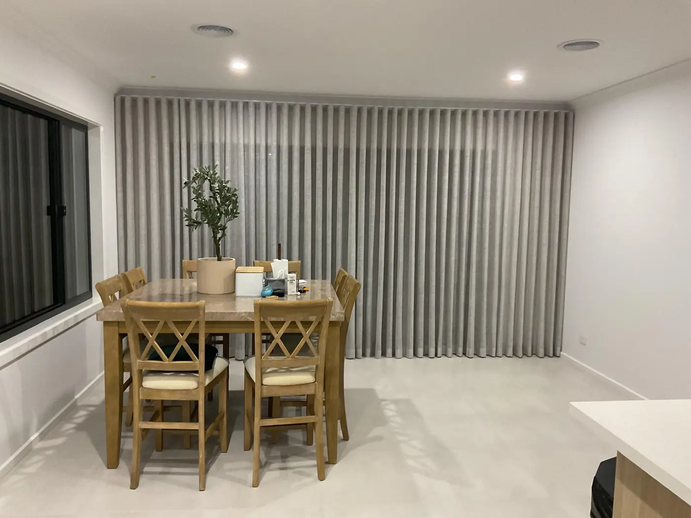 Custom floor-to-ceiling grey sheer curtains installed in a Melbourne dining room