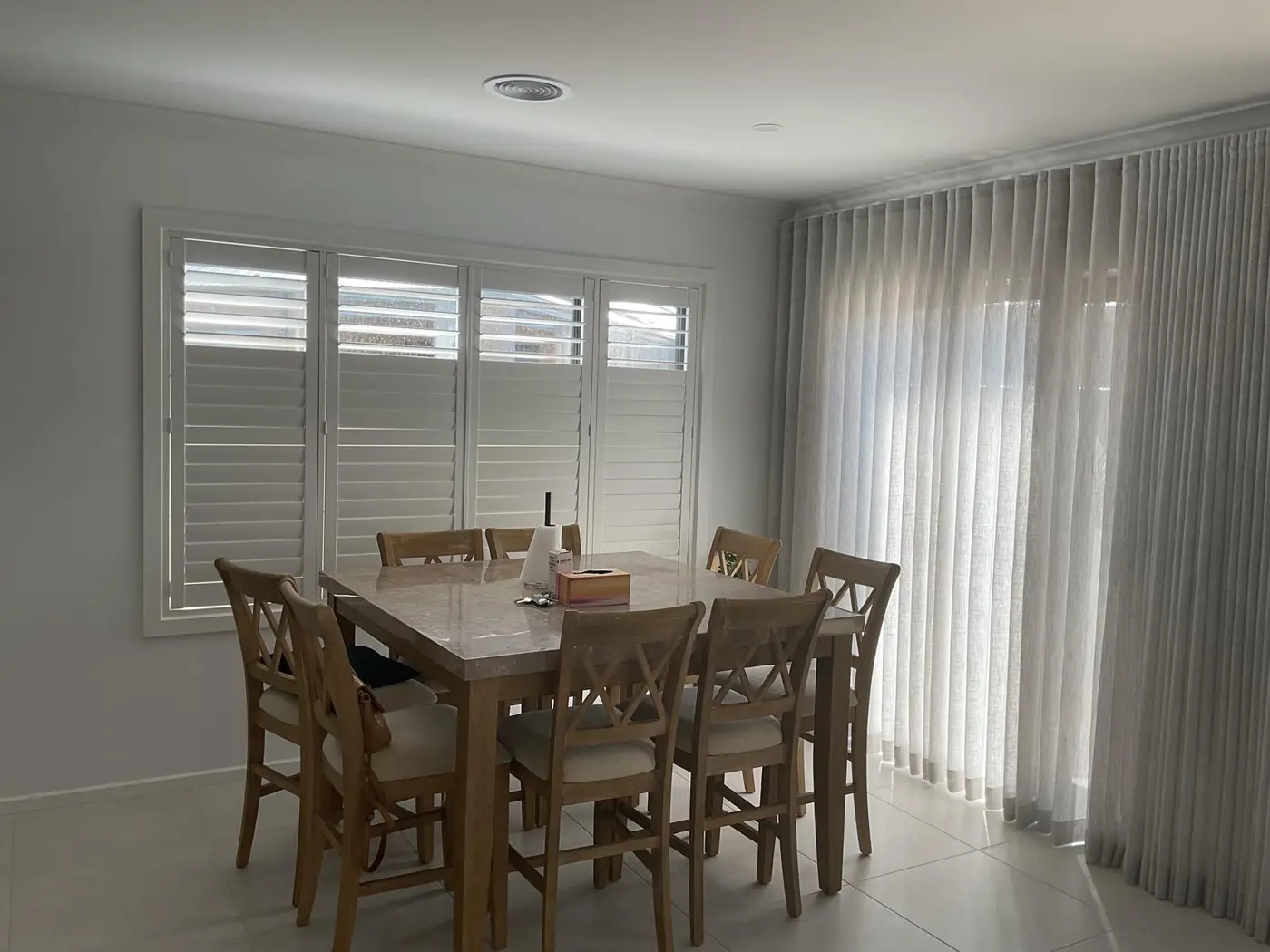 Sheer curtains paired with plantation shutters in a Melbourne dining room